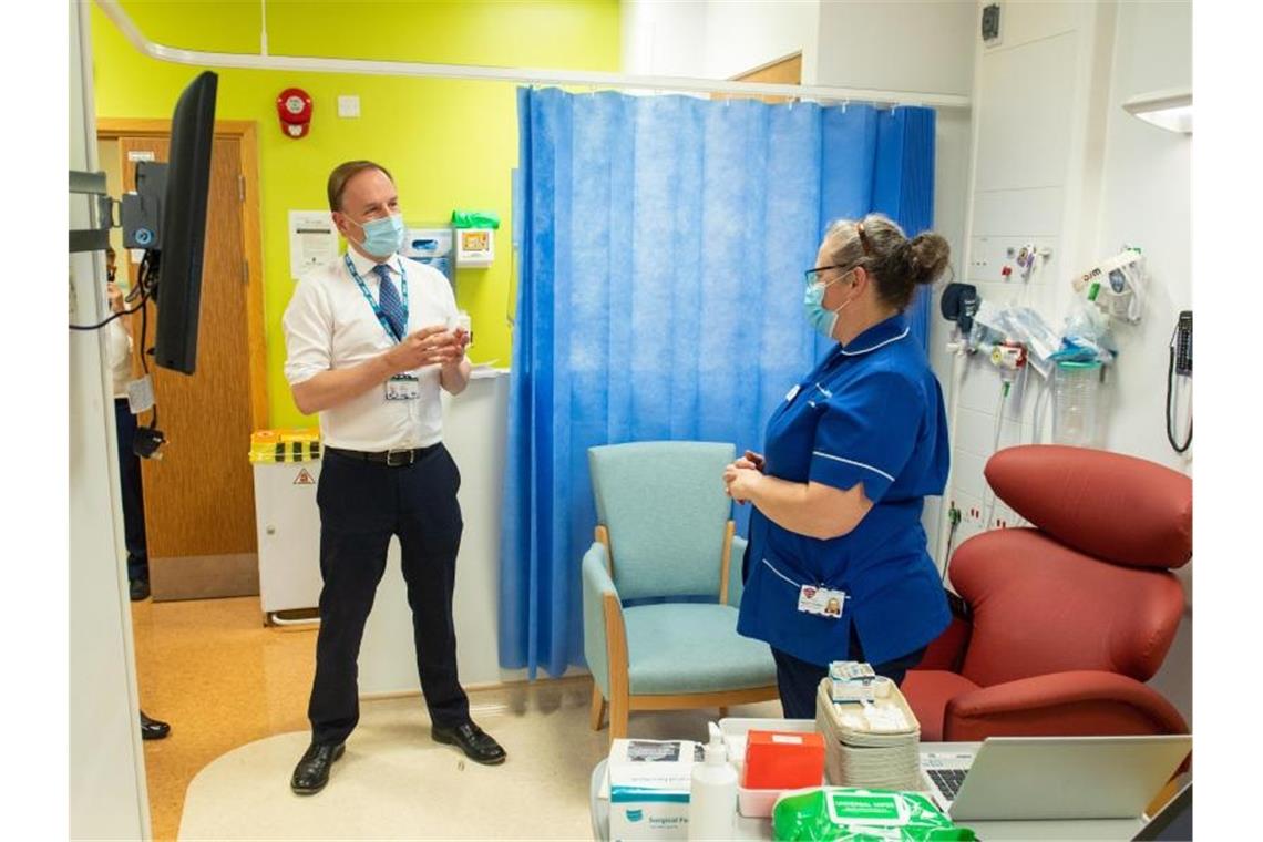 90-jährige Britin erhält erste Corona-Impfung Simon Stevens, Chef des englischen Gesundheitsdienstes, im Gespräch mit einer Mitarbeiterin des Krankenhauses "Royal Free" in London. Foto: Dominic Lipinski/PA Wire/dpa