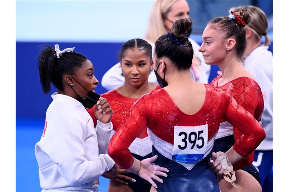 Simone Biles spricht mit ihren Teamgefährtinnen, nachdem sie das Mannschaftsfinale verletzungsbedingt vorzeitig abbrechen musste. Foto: Marijan Murat/dpa