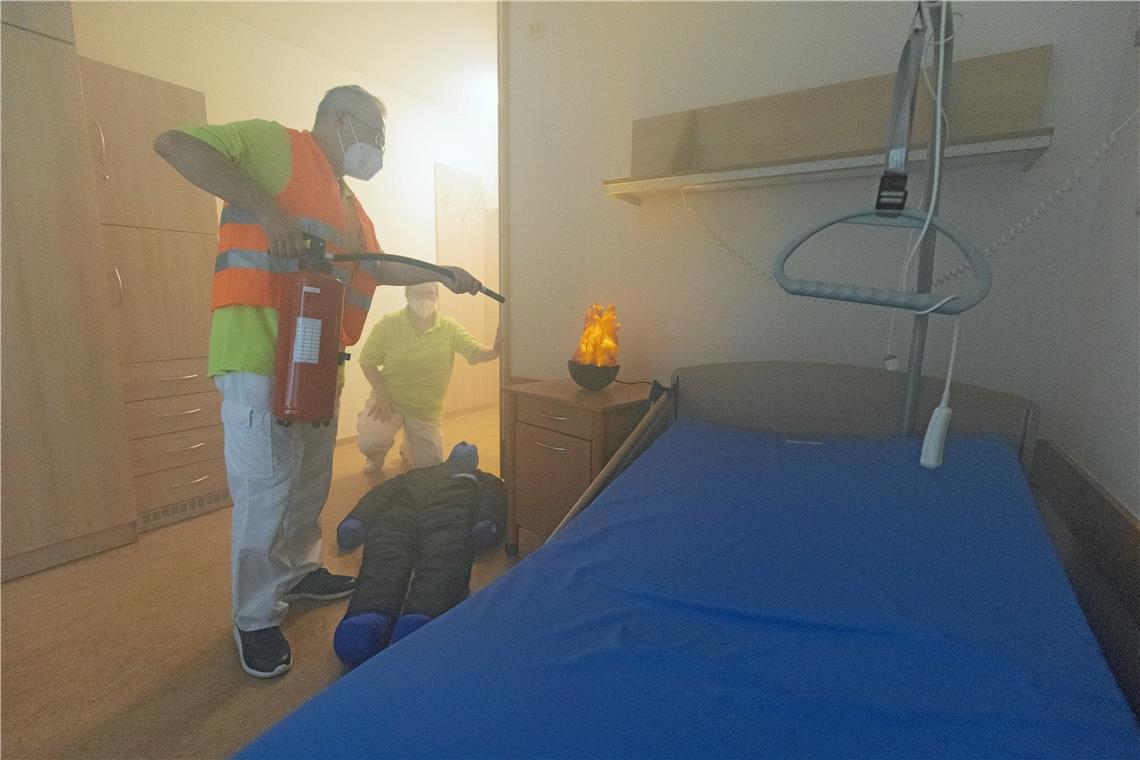 Simulation eines Feuers im Zimmer einer Bewohnerin. Eine Person kümmert sich um die verletzte „Person“, die andere löscht das Feuer.