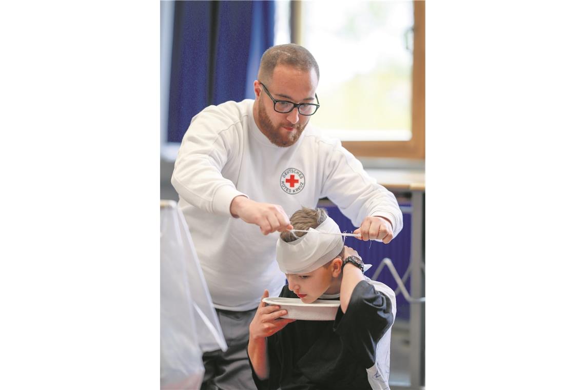 Wenn der Dienst
am Nächsten
Freude bereitet Simulierter Einsatz: ein Jugendlicher ist gestürzt und soll erstversorgt werden. Die Wunde am Kopf ist nur geschminkt (links), der Verband ist aber echt. Fotos: A. Becher