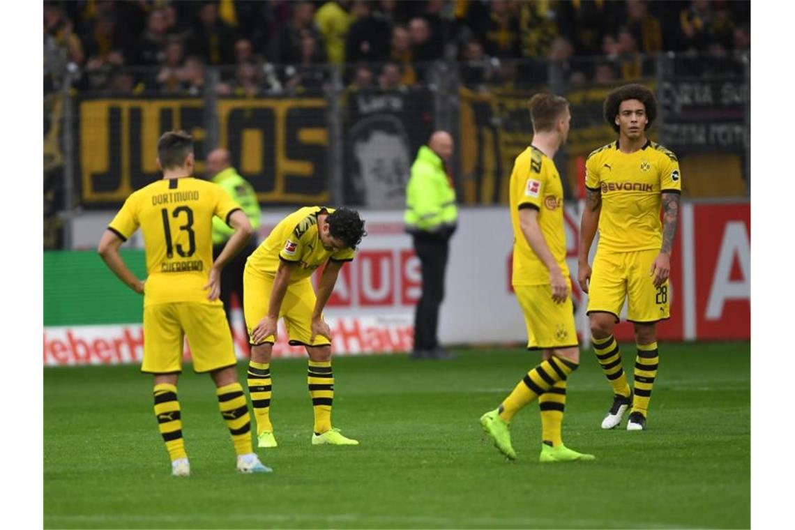 Sind sich selbst ein Rätsel: Die BVB-Spieler stehen nach dem Remis beim SC Freiburg mit hängenden Köpfen auf dem Spielfeld. Foto: Patrick Seeger/dpa