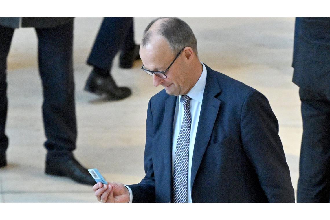Skeptischer Friedrich Merz mit Stimmkarte im Bundestag.