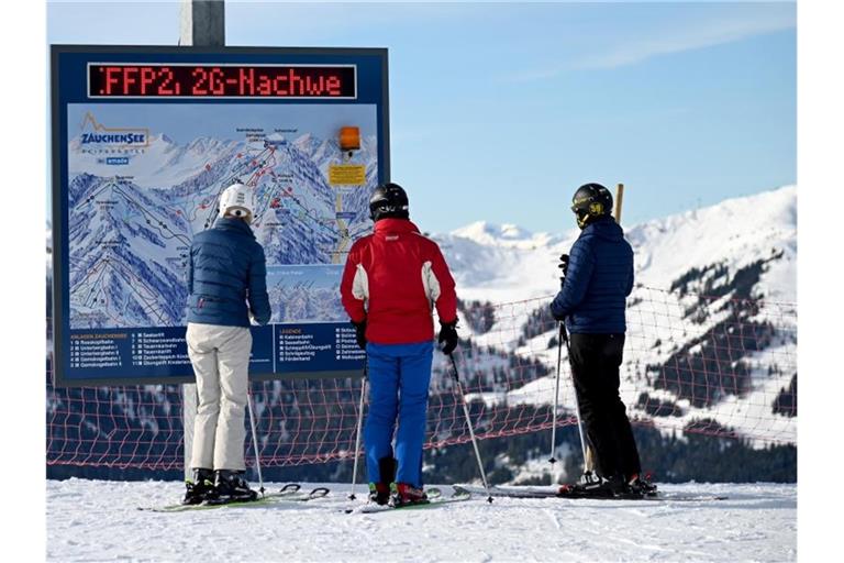Skifahrer vor einer Informationstafel mit der Aufforderung nach FFP2-Masken und 2G-Nachweis im Skigebiet Altenmarkt-Zauchensee. Foto: Barbara Gindl/APA/dpa