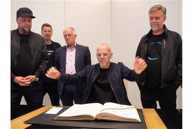 Smudo (l-r), Michi Beck, Stuttgarts Oberbürgermeister Fritz Kuhn (Bündnis 90/Die Grünen), Thomas D. und And.Ypsilon von der Hip Hop-Band "Die Fantastischen Vier" stehen bzw. sitzen hinter dem Goldenen Buch der Stadt Stuttgart. Foto: Marijan Murat