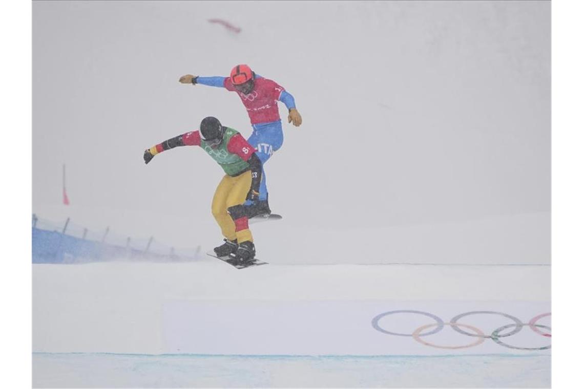 Snowboardcrosser Martin Nörl (l) rast beim Team-Wettbewerb über die Piste. Foto: Gregory Bull/AP/dpa