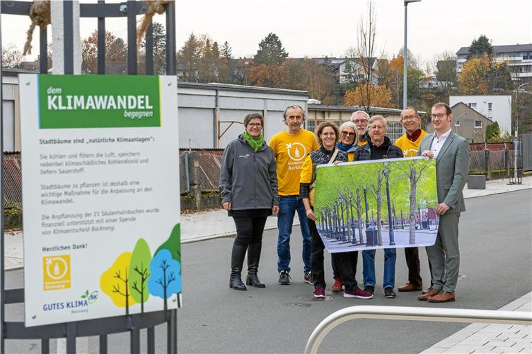 So grün wie auf dem Plakat soll es bald in der Schöntaler Straße aussehen. Klimamanagerin Simone Lebherz (links) und OB Maximilian Friedrich (rechts) freuen sich über die Spende der Gruppe Klimaentscheid Backnang. Übergeben wird sie von den Mitgliedern (von links) Achilles Bückle, Katharina Mühleisen, Maike Ribbeck, Martin Fischer, Gerd Mühlnikel und Bertram Ribbeck. Foto: Alexander Becher