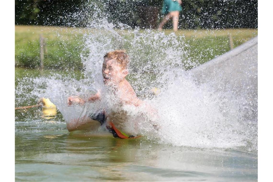 So lässt sich die Hitze aushalten: Ein Junge rutscht eine Wasserrutsche hinunter. Foto: Thomas Warnack/dpa