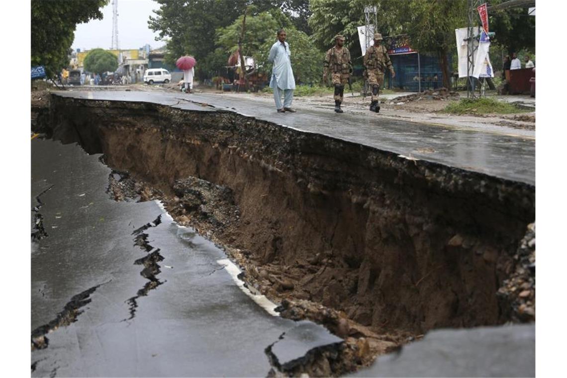 Soldaten gehen an einer stark beschädigten Straße in Jatla vorbei. Foto: Anjum Naveed/AP