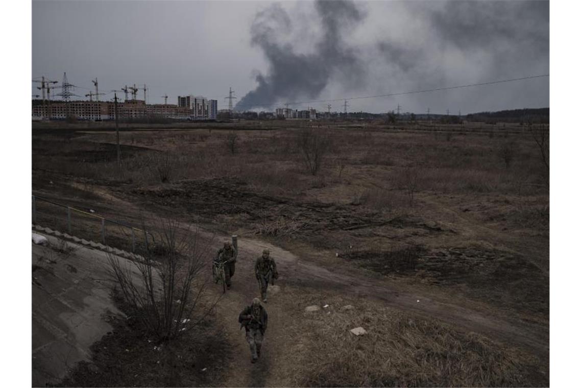Krieg gegen die Ukraine: So ist die Lage Soldaten gehen einen Weg entlang, während Rauch in Irpin nordwestlich von Kiew aufsteigt. Foto: Felipe Dana/AP/dpa