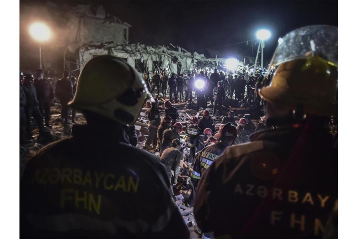 Soldaten und Feuerwehrleute vor zerstörten Häusern in Ganja, Aserbaidschans zweitgrößter Stadt. Foto: Ismail Coskun/IHA/AP/dpa