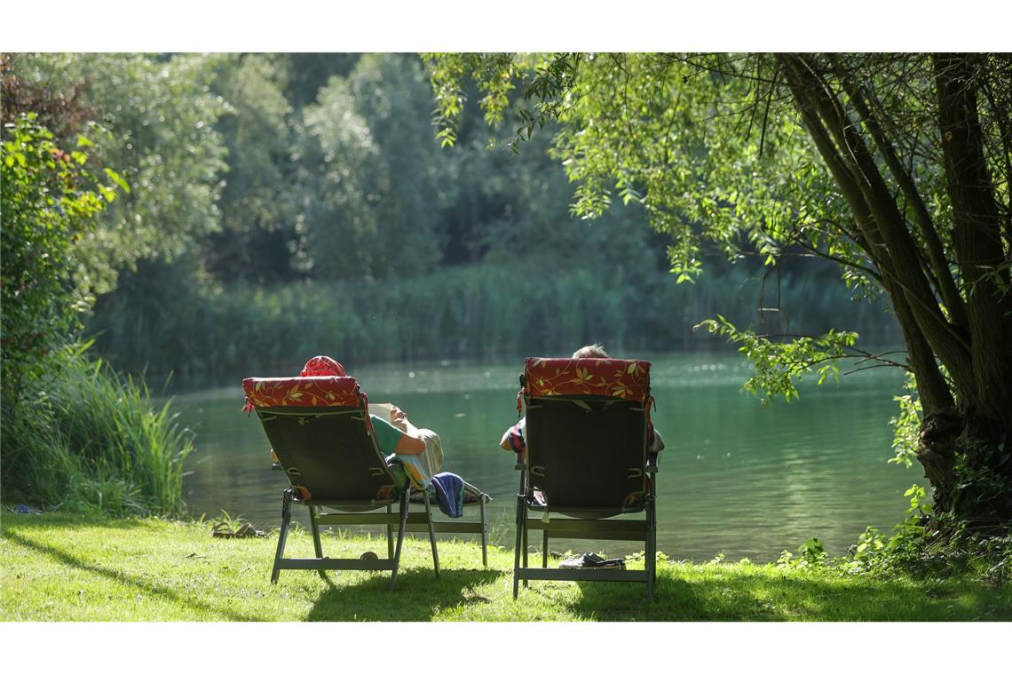 Bilder des Tages Sommerwetter in Deutschland. Ein Mann und eine Frau liegen am Ufer des Schwarzachtalsees in Liegestühlen und sonnen sich.