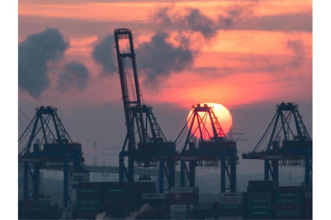 Sonnenuntergang hinter den Containerbrücken des HHLA Containerterminal Tollerort in Hamburg. Die Corona-Krise reißt tiefe Löcher in den Staatshaushalt. Foto: picture alliance / Christian Charisius/dpa