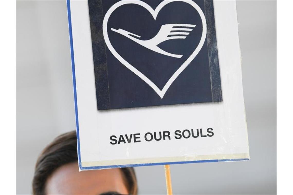 SOS: Ein Lufthansa-Flugbegleiter trägt ein Plakat mit der Aufschrift „Save our souls“. Foto: Arne Dedert/dpa