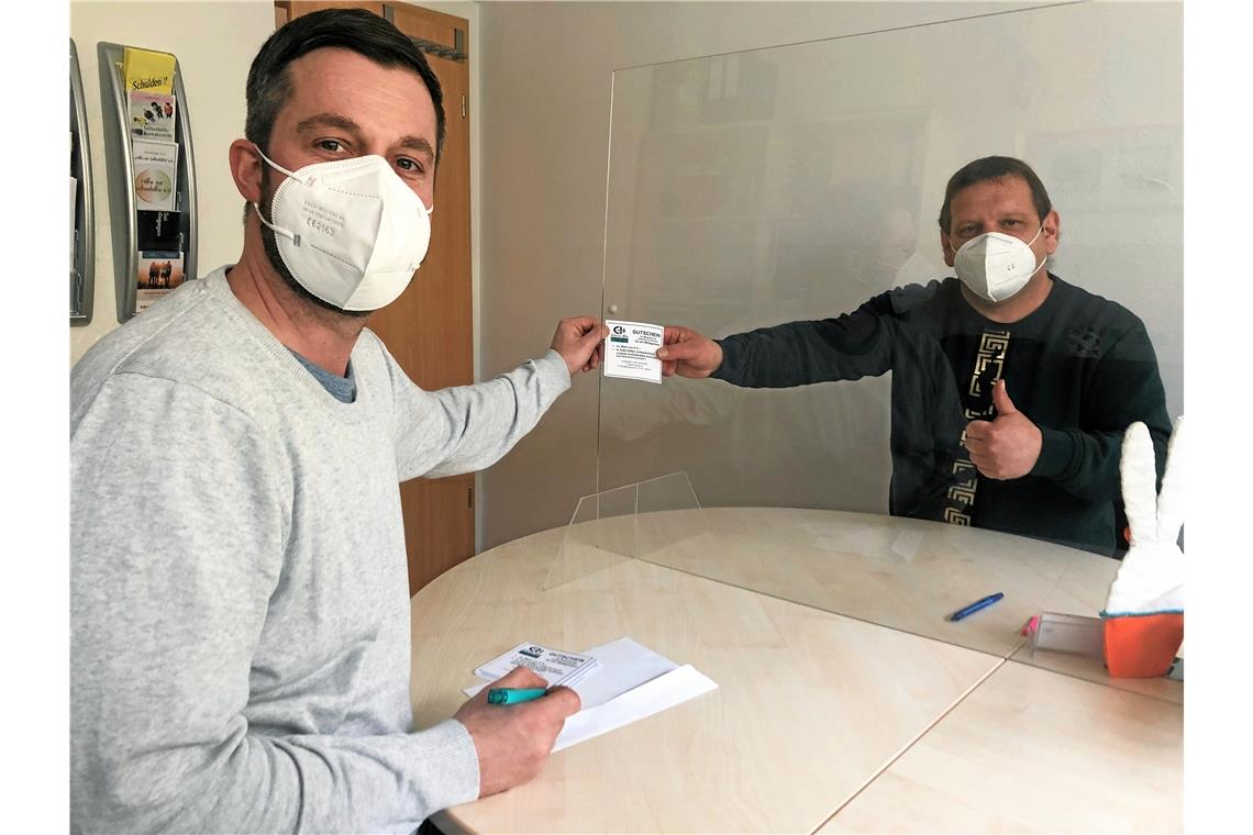 Sozialarbeiter Swen Schreier (links) übergibt einen Essensgutschein. Foto: Erlacher Höhe