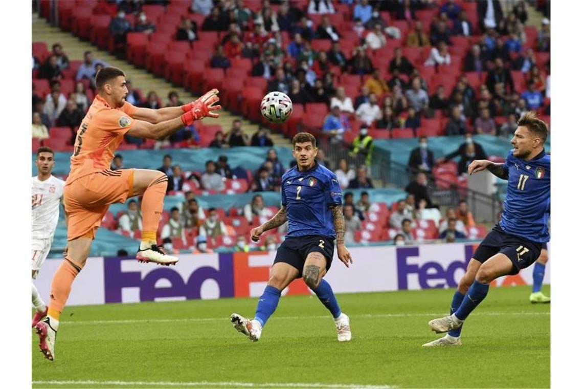 Spaniens Torwart Unai Simon (l) fängt den Ball vor Italien-Torjäger Ciro Immobile (3.v.r). Foto: Andy Rain/Pool EPA/AP/dpa