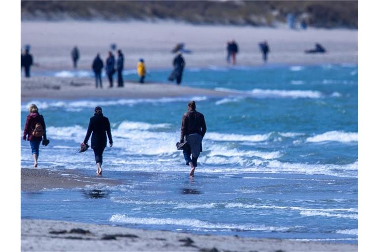 Spaziergänger am Strand von WArnemnünde. Foto: Jens Büttner/dpa-Zentralbild/dpa