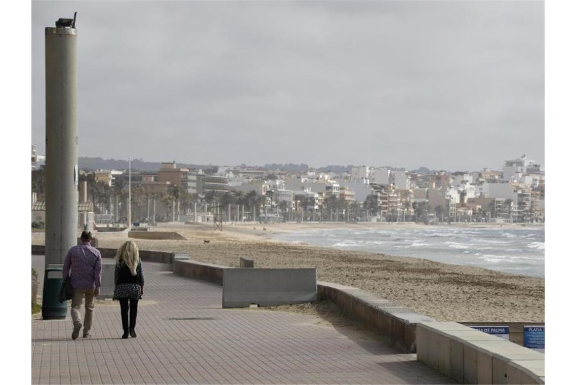 Spaziergänger auf der Promenade am Strand von Arenal. Foto: Clara Margais/dpa