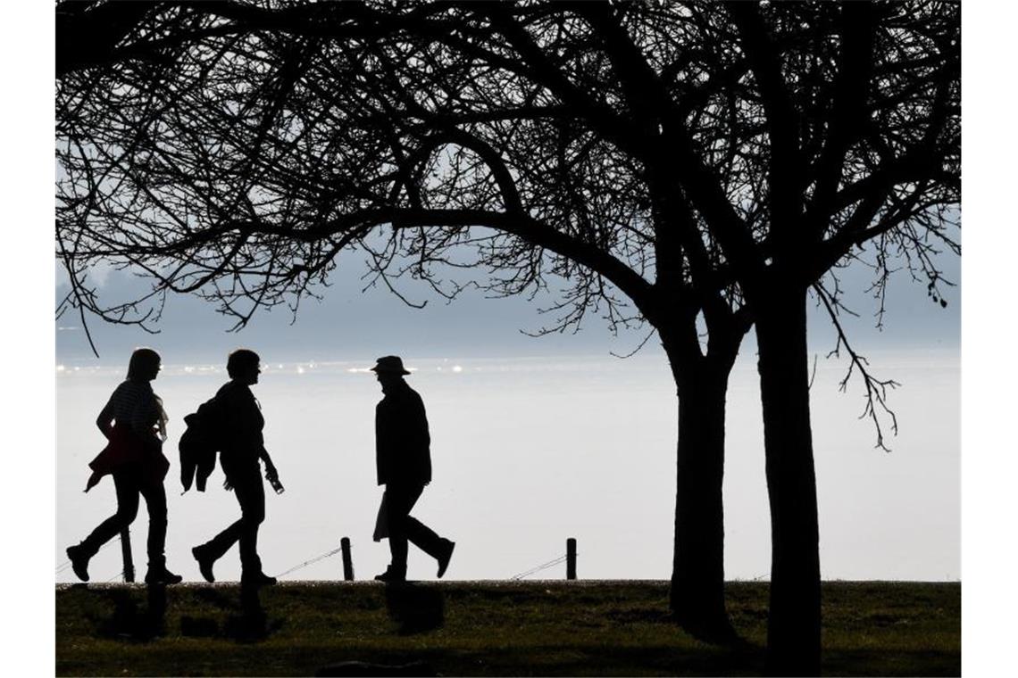 Spaziergänger gehen auf einem Wanderweg am Bodensee. Foto: Felix Kästle/dpa/Archivbild