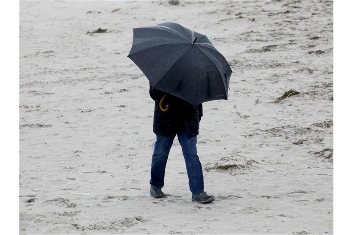 Orkane überqueren Deutschland Spaziergänger mit wetterfester Kleidung und Regenschirm am Ostseestrand. Foto: Bernd Wüstneck/dpa-Zentralbild/dpa