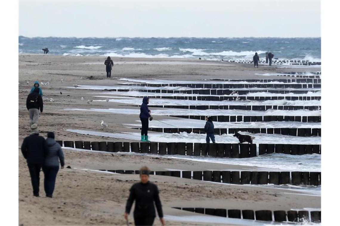 Spaziergänger sind am Strand bei Graal-Müritz unterwegs. Foto: Bernd Wüstneck/dpa-Zentralbild/dpa