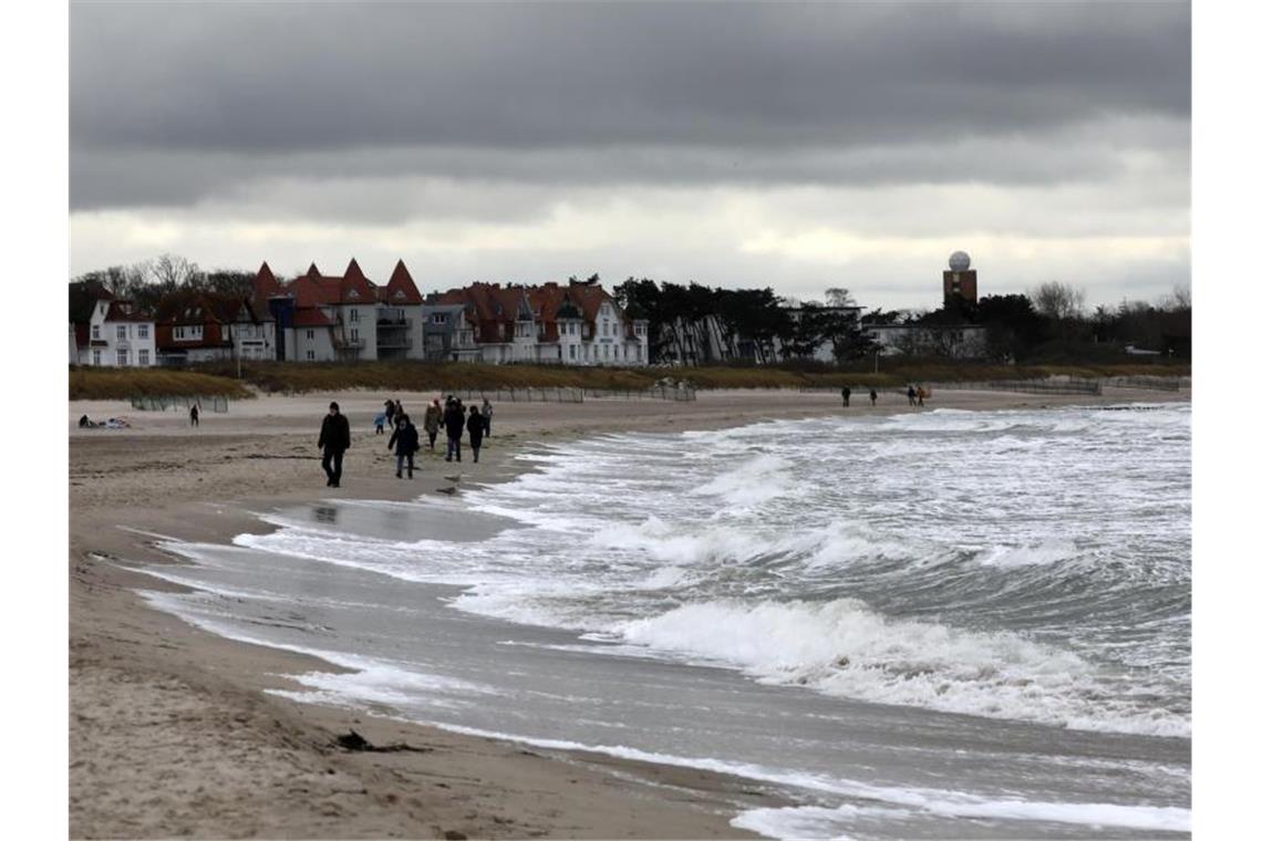 Spaziergänger sind bei stürmischem Wind an der aufgewühlten Ostsee in Warnemünde unterwegs. Foto: Bernd Wüstneck/dpa-Zentralbild/dpa