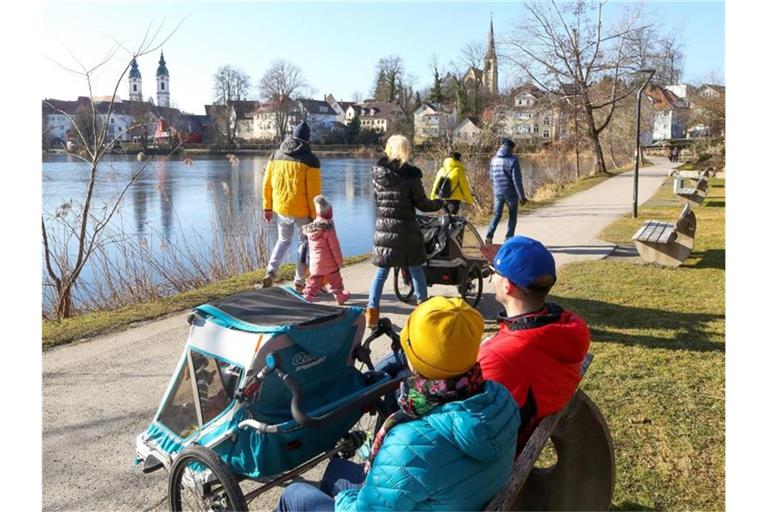 Spaziergänger sind im Sonnenschein am Stadtsee unterwegs. Foto: Thomas Warnack/dpa