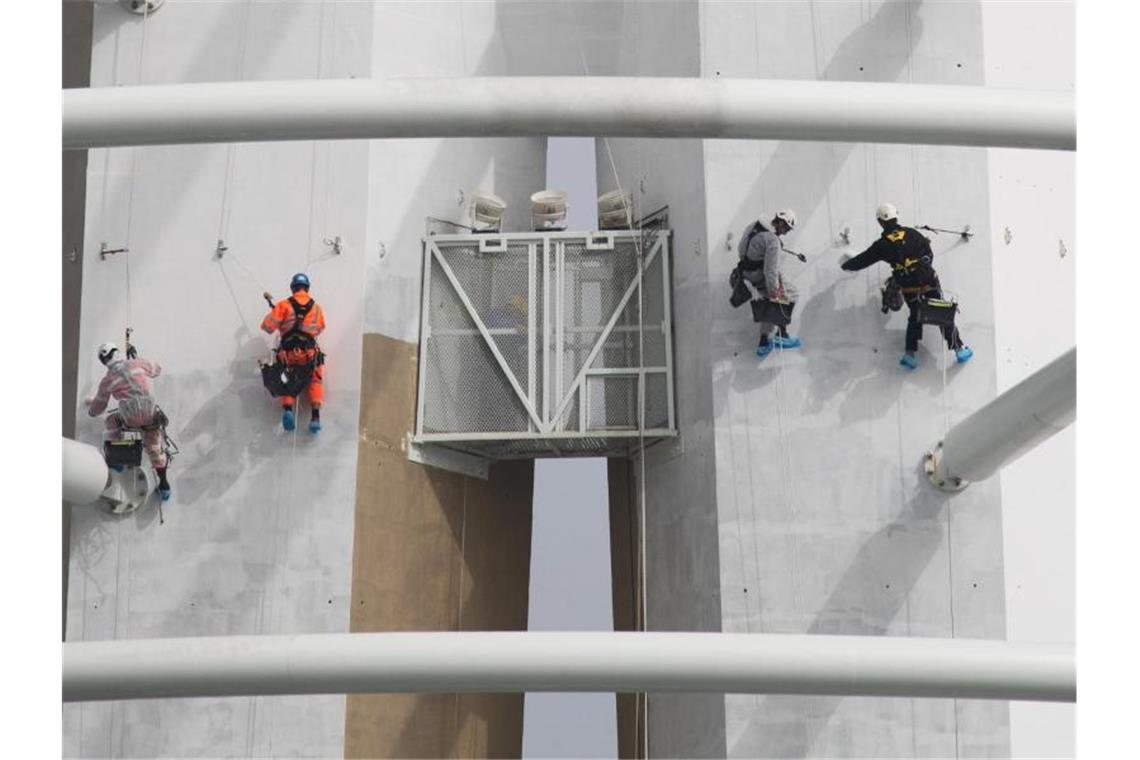 Spezialisten klettern an der Außenseite des „Spinnaker Towers“ und streichen dabei den Aussichtsturm im Hafen von Portsmouth. Foto: Andrew Matthews/PA Wire/dpa