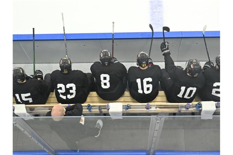 Spieler der deutschen Eishockey-Nationalmannschaft sitzen bei einer Trainingseinheit auf der Bank. Foto: Peter Kneffel/dpa