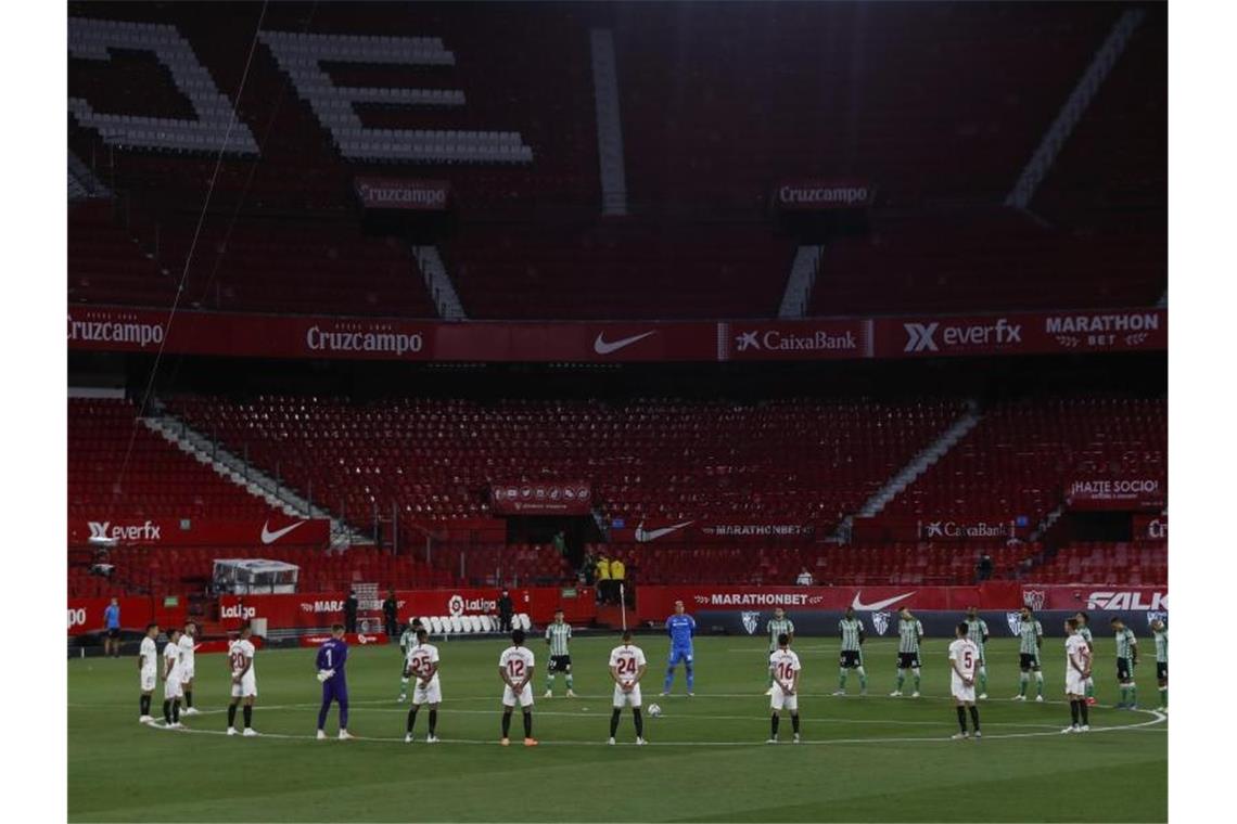 Spieler des FC Sevilla und Real Betis Sevilla legen eine Schweigeminute für die Coronavirus-Todesopfer ein. Foto: Str/AP/dpa