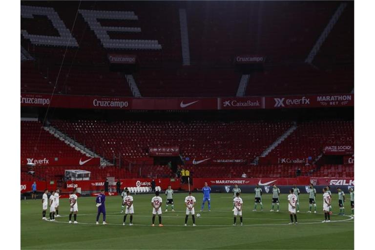 Spieler des FC Sevilla und Real Betis Sevilla legen eine Schweigeminute für die Coronavirus-Todesopfer ein. Foto: Str/AP/dpa