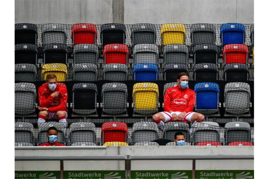 Spieler von Fortuna Düsseldorf sitzen auf der Tribüne. Foto: Sascha Schuermann/AFP-Pool/dpa