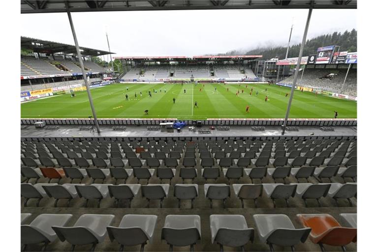 Spieler von Freiburg und Bremen wärmen sich vor dem Spiel im leeren Stadion auf. Foto: Thomas Kienzle/AFP-Pool/dpa