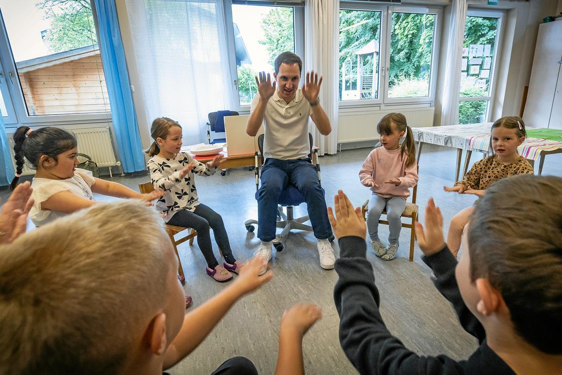 Sprechen, klatschen, stampfen – Lehrer Leon Sieber von der Plaisirschule vermittelt den Kindern in der Kita Christkönig auf spielerische Weise den Umgang mit der deutschen Sprache. Dadurch sollen sie sich bei der Einschulung leichter tun. Foto: Alexander Becher