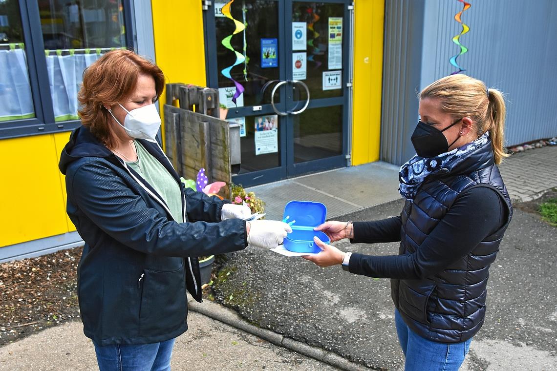 Spucktestübergabe vor dem Weissacher Kindergarten Wiesengrün: Einrichtungsleiterin Daniela Mattern (links) händigt der Elternbeiratsvorsitzenden Melina Hahn die Tests für die Folgewoche aus, die in einer leeren Vesperdose ihren Platz finden. Foto: T. Sellmaier