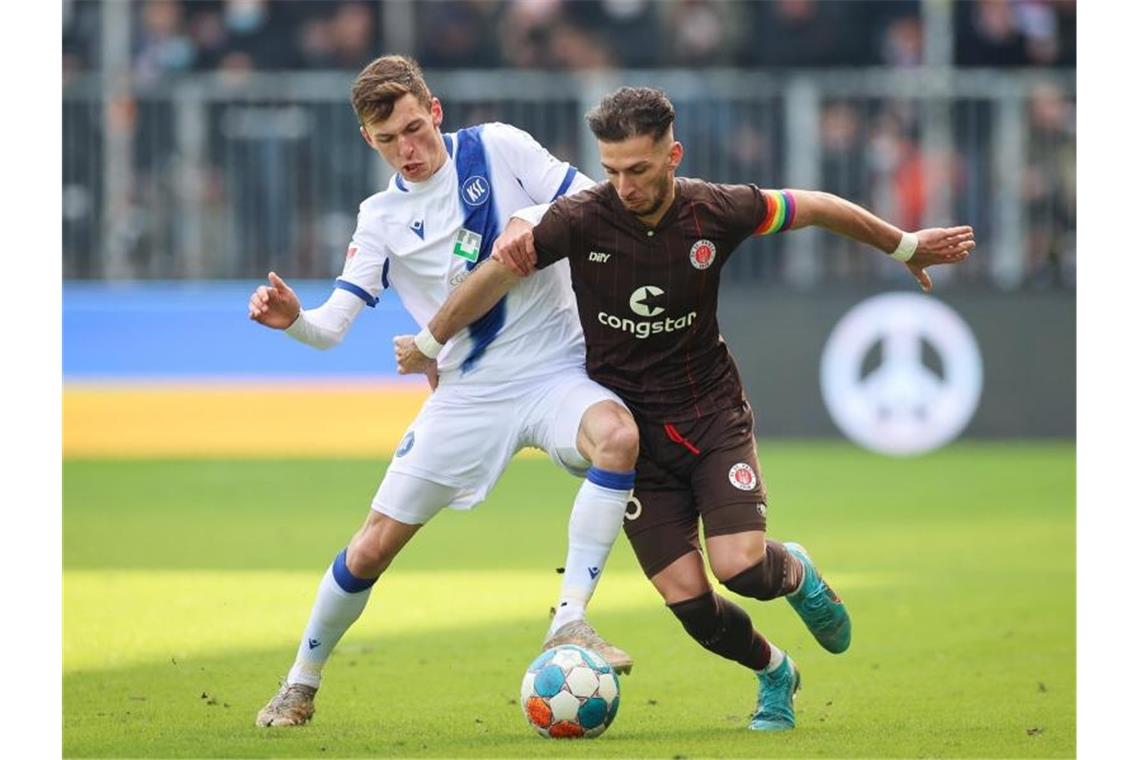KSC nach Pokal-Aus und Liga-Niederlage müde St. Paulis Leart Paqarada (r) und Karlsruhes Benjamin Goller kämpfen um den Ball. Foto: Christian Charisius/dpa