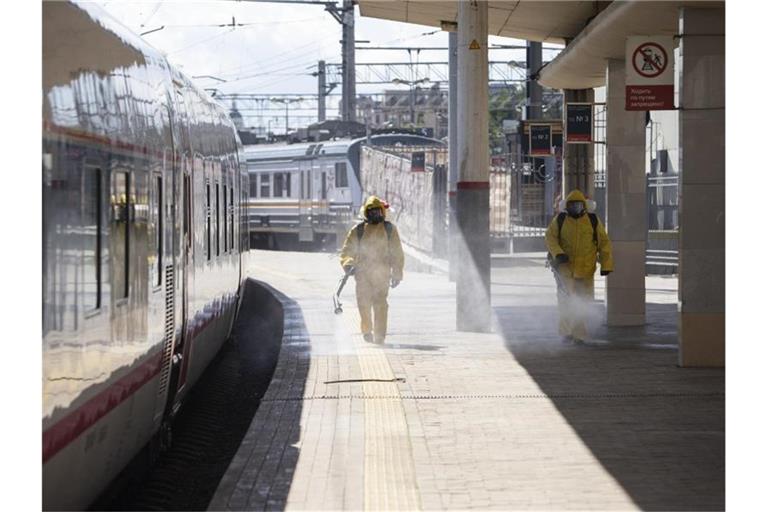 Staatliche Mitarbeiter in Schutzkleidung desinfizieren den Kiewer Bahnhof in Moskau. Foto: Alexander Zemlianichenko Jr/AP/dpa