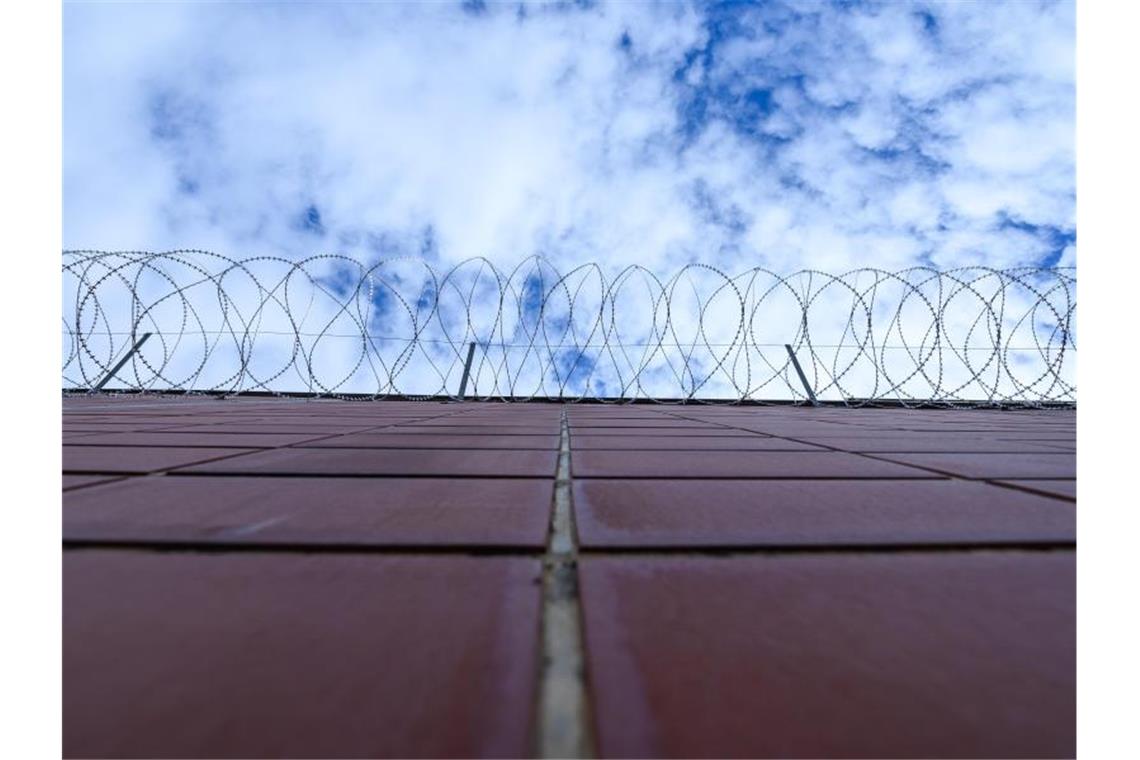 Stacheldrahtzaun hängt an einer Mauer einer Justizvollzugsanstalt. Foto: Silas Stein/dpa/Symbolbild