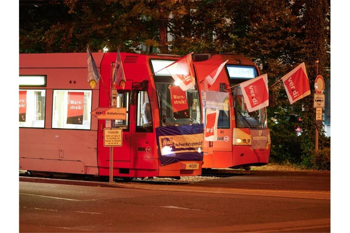 Stadtbahnwagen mit Flaggen der Gewerkschaft Verdi stehen vor einem Depot der Kölner Verkehrsbetriebe (KVB). Durch die Landesweiten Warnstreiks im öffentlichen Personennahverkehr fallen in Köln die Fahrten der Bahn aus. Foto: Henning Kaiser/dpa
