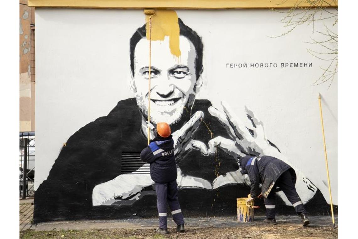 Städtische Arbeiter übermalen ein Graffiti mit dem Konterfei von Alexej Nawalny. Auf der Wand ist zu lesen: „Held unserer Zeit“. Foto: Ivan Petrov/AP/dpa/Archiv