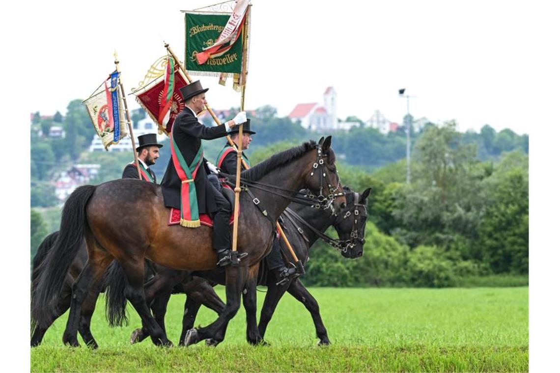 Große Reiterprozession: Frauen bei „Blutritt“ zugelassen Standartenträger und Reiter aus Grünkraut reiten beim traditionellen „Blutritt“ einen Weg entlang. Foto: Felix Kästle/dpa/Archivbild