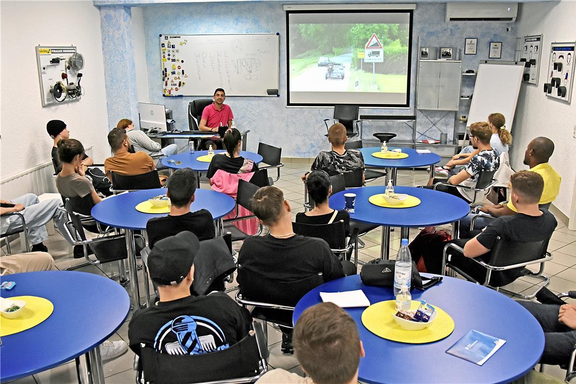 Backnanger Büffeln in den Ferien für den Führerschein Stathis Tsifoutis (pinkes Hemd) von der Fahrschule Euro Drive erklärt den Fahrschülerinnen und Fahrschülern den umweltbewussten Umgang mit einem Kraftfahrzeug und greift dafür auch auf Hilfsmittel wie Filmclips oder ein Modellauto zurück. Foto: Tobias Sellmaier
