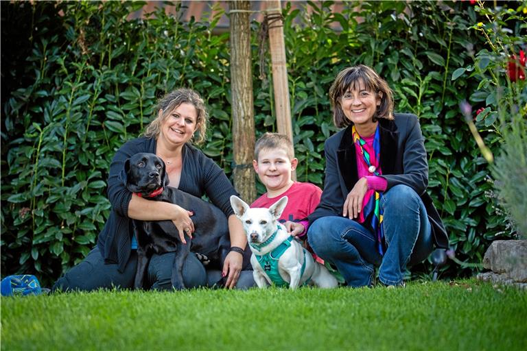 Stefanie Winter (links) und ihr Sohn Louis posieren im Garten mit Beate Iris Müller vom Verein „Tierhilfe Hoffnung“ und den Hunden Kiki-Lou und Juli fürs Foto.  Foto: A. Becher