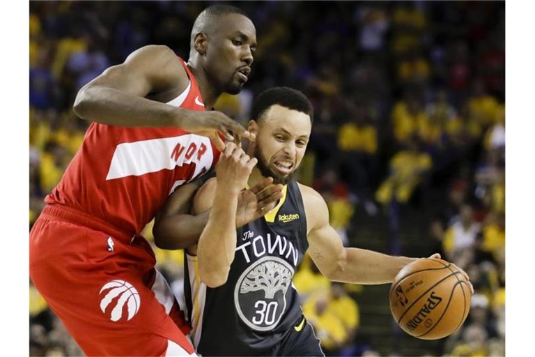 Stephen Curry (r) von den Golden State Warriors behauptet sich gegen Serge Ibaka von den Toronto Raptors. Foto: Ben Margot/AP