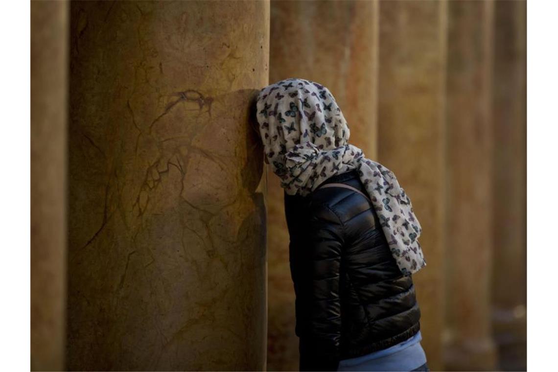 Christen in aller Welt feiern Weihnachten Stille Einkehr: Eine Frau betet in der Geburtskirche in Bethlehem. Foto: Majdi Mohammed/AP/dpa