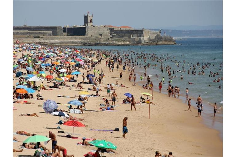 Strandbesucher an einem heißen Nachmittag am Strand Carcavelos. Foto: Pedro Fiuza/XinHua/dpa