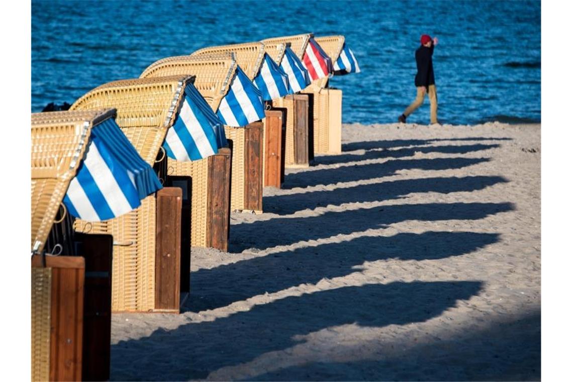 Strandkörbe werfen am Abend lange Schatten auf den Strand an der Ostsee bei Lübeck-Travemünde. Foto: Daniel Bockwoldt/dpa