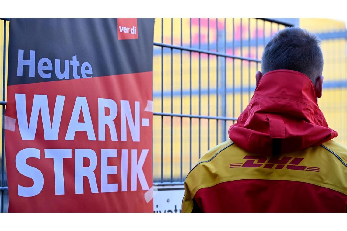Millionen Sendungen bleiben wegen Post-Warnstreiks liegen Streikposten am Werkstor: Ein DHL-Mitarbeiter hat die Arbeit niedergelegt und schaut auf eine Zustellbasis, in der er sonst arbeitet.