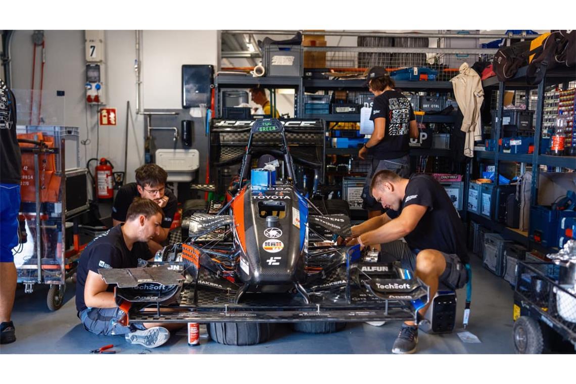 Studenten an einem Rennwagen beim Konstruktionswettbewerb Formula Student Germany am Hockenheimring. Für Unternehmen ist das Event auch ein Recruitingpool, weil sie mit den Ingenieuren von morgen in Kontakt kommen.
