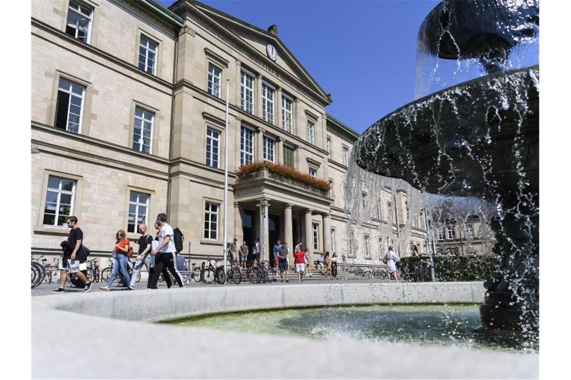 Studentinnen und Studenten laufen vor der Universität Tübingen an einem Brunnen vorbei. Foto: Edith Geuppert/dpa/archivbild