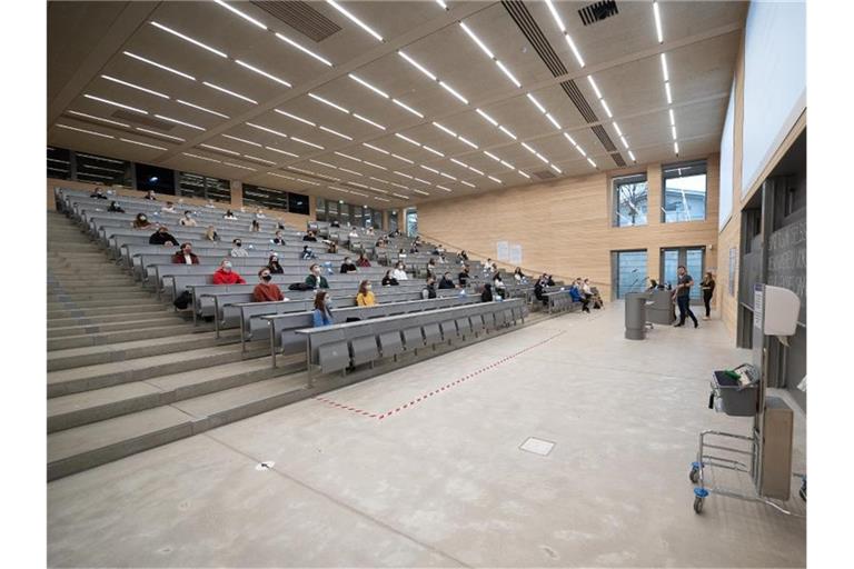Studierende mit Mund- und Nasenmaske sitzen in der Begrüßungsveranstaltung für Studierende im ersten Semester an der Universität Hohenheim. Foto: Sebastian Gollnow/dpa